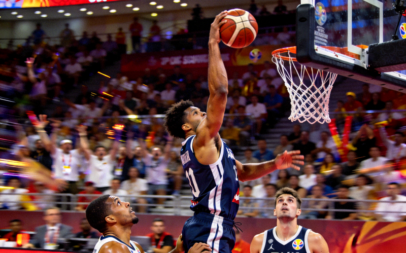 篮球世界杯比赛中球员完成隔人暴扣的震撼瞬间，展现惊人弹跳力