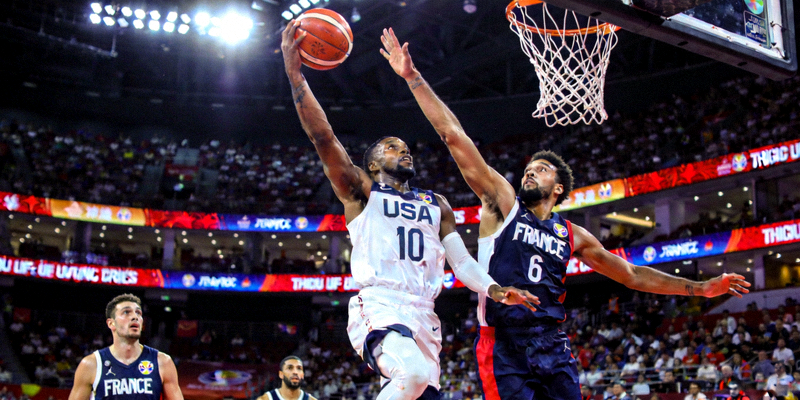 篮球世界杯小组赛美国队对阵法国队的激烈比赛现场，球员突破上篮瞬间